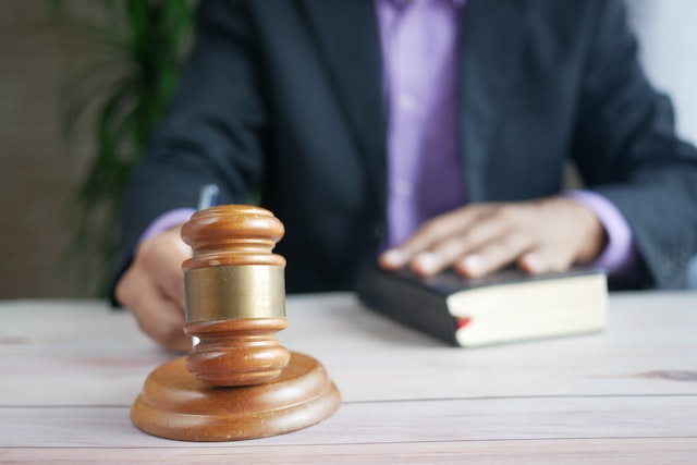 person hitting a gavel with their other hand on a law book